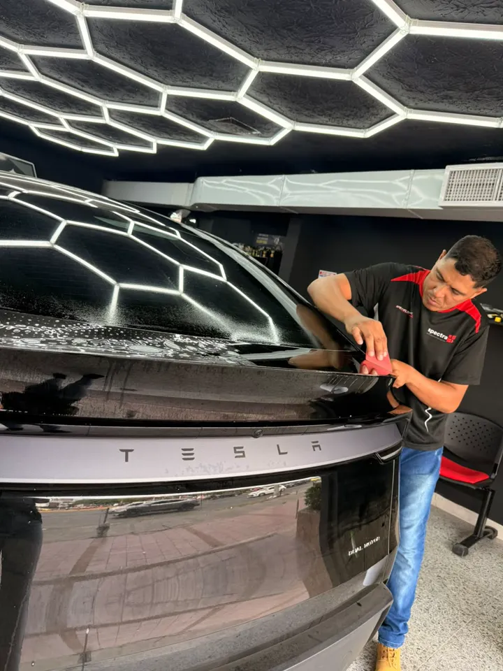 Instalador de Polariglass trabajando el vidrio trasero de un Tesla en Cali